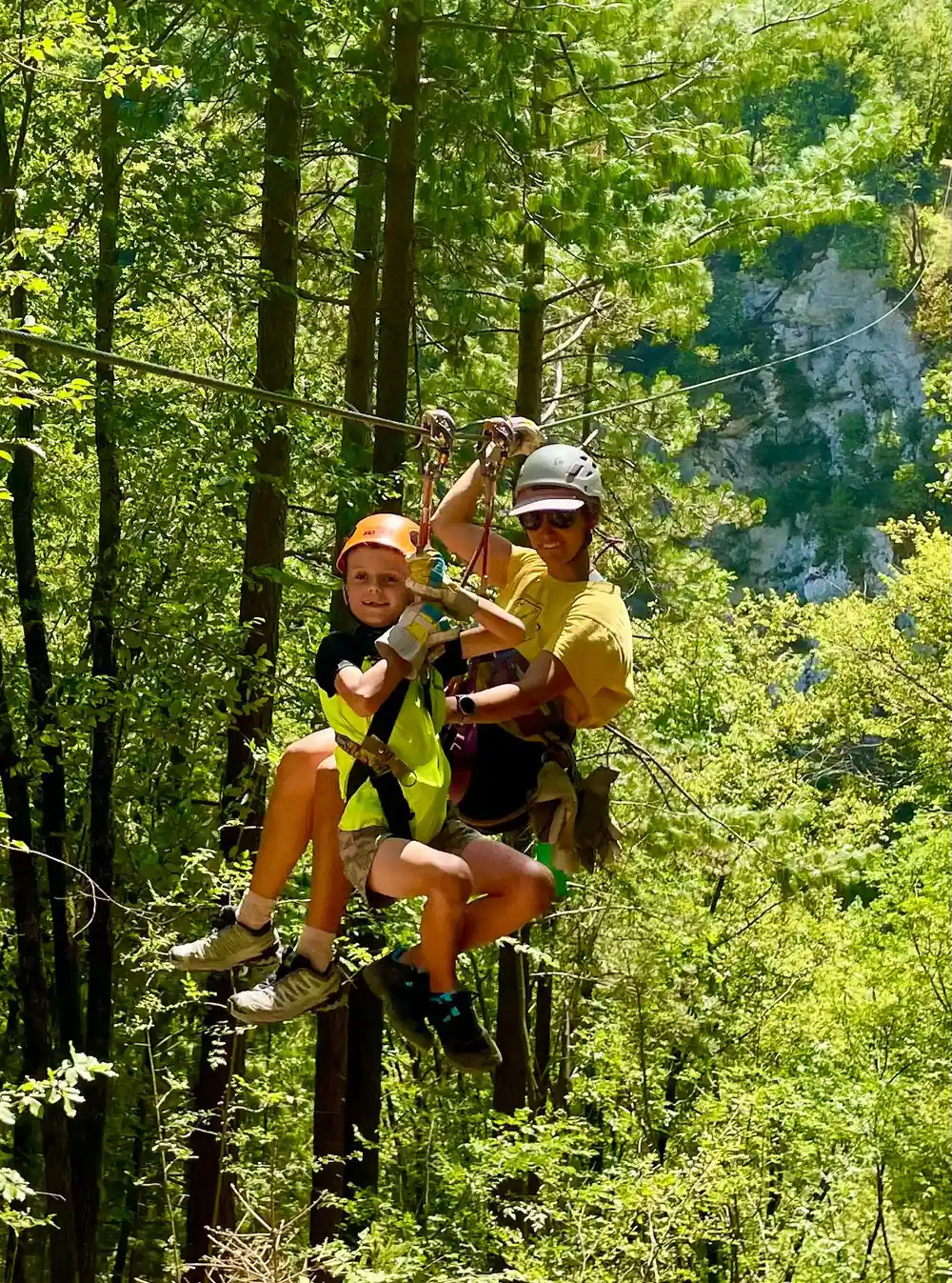 A guide and a rider clipped in beneath the trees