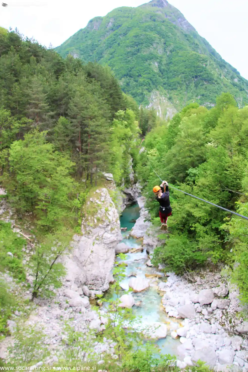 A rider on the wire high above the turquoise river